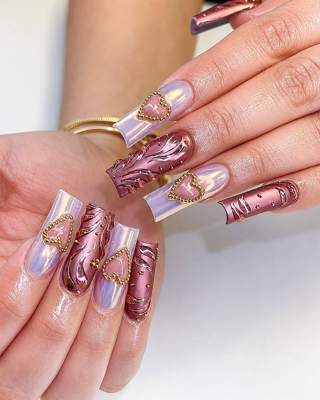 Rose chrome nails with glossy heart accents by My Royal Nails & Spa in Humble, TX